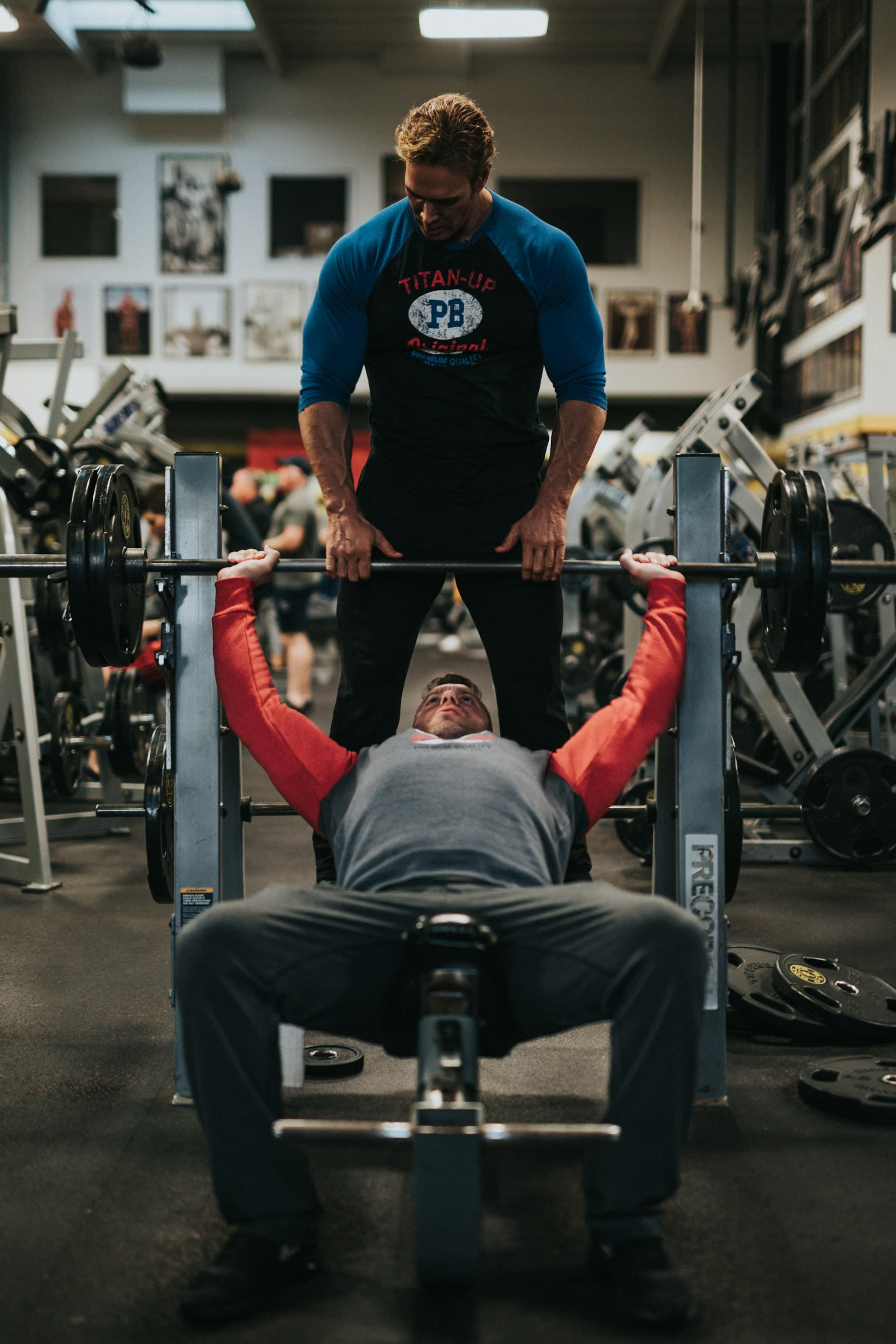 Personal trainer acompanhando um aluno no supino